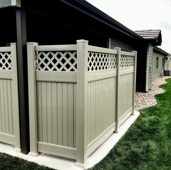 Grey vinyl privacy fence installed around concrete patio.